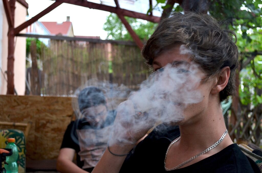 young person smoking marijuana with cloud of smoke in front of their face