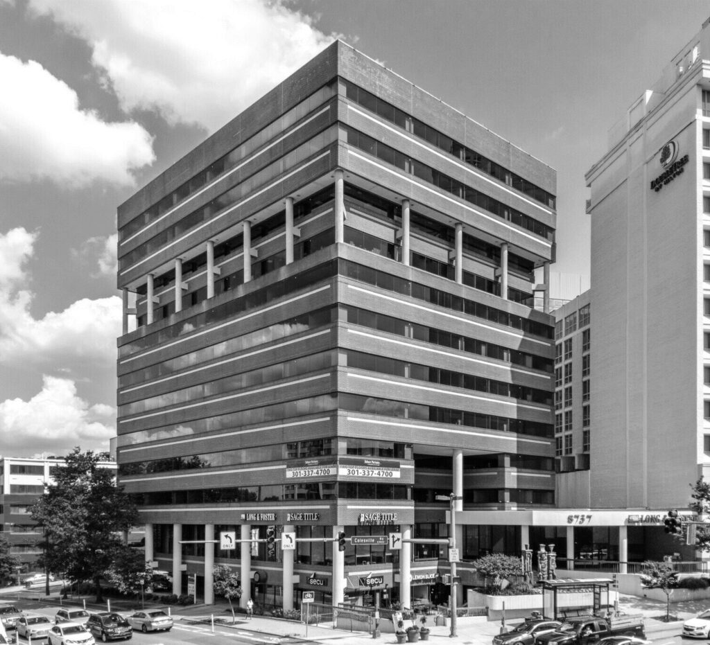 Office building in black and white with cloud in the background.